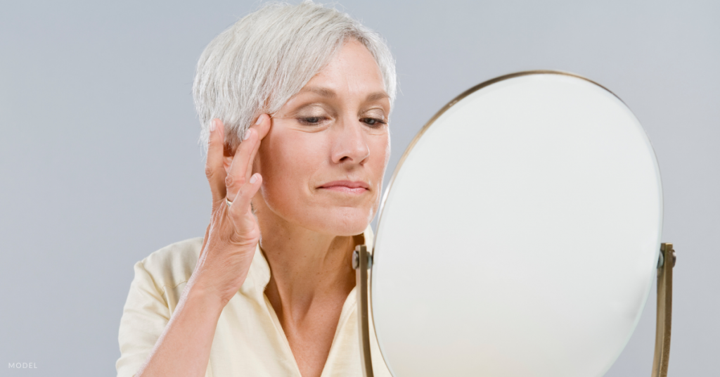 An older woman looking at herself in the mirror (model).