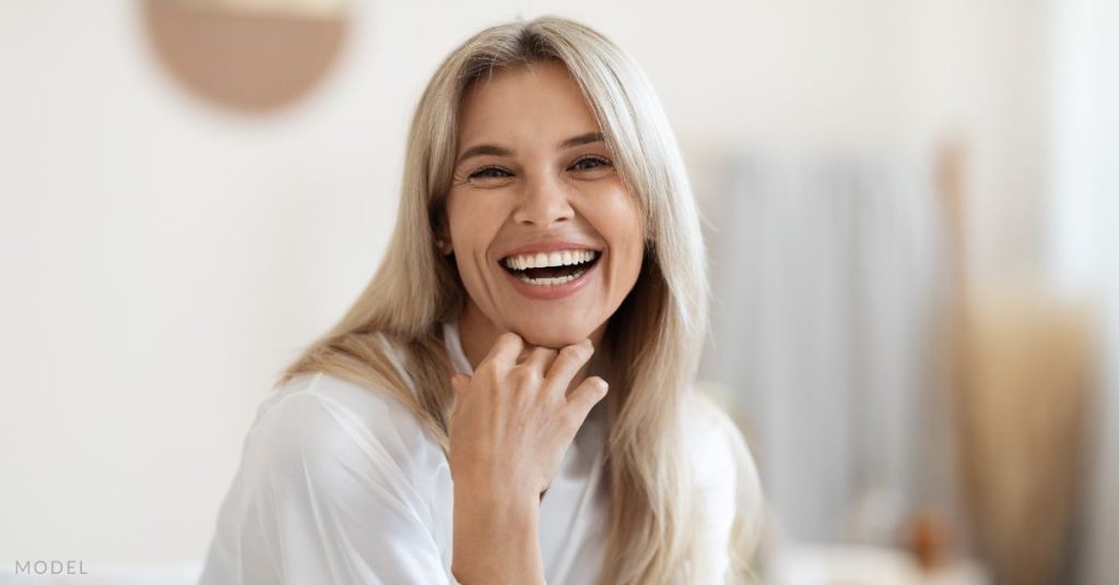 A woman touching her chin and smiling (model)