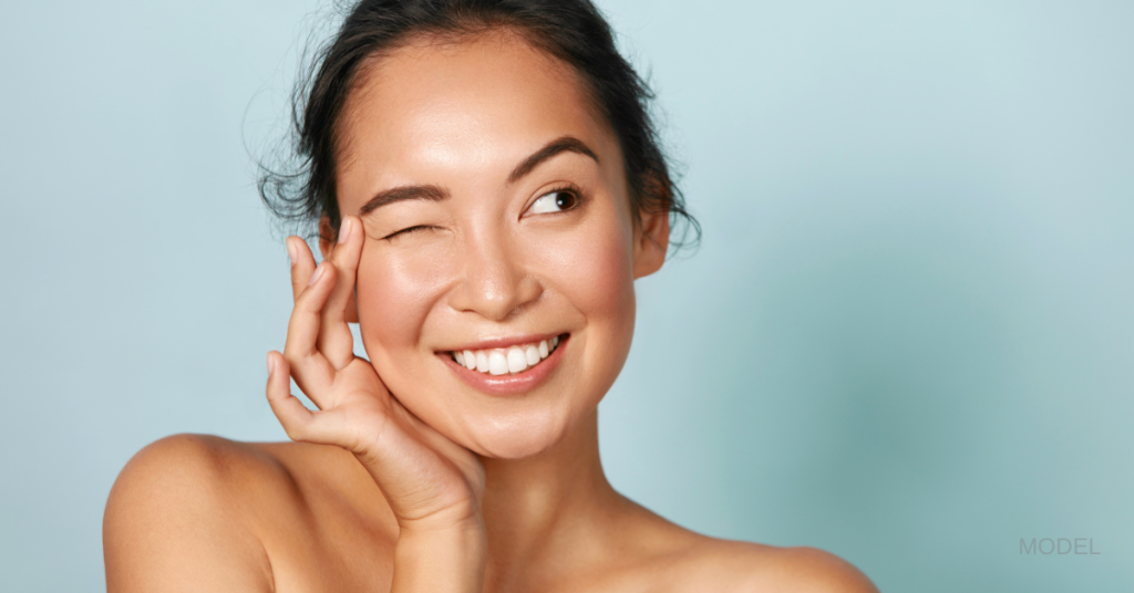 A woman with glowing skin, winking while looking off to the side. (Model)