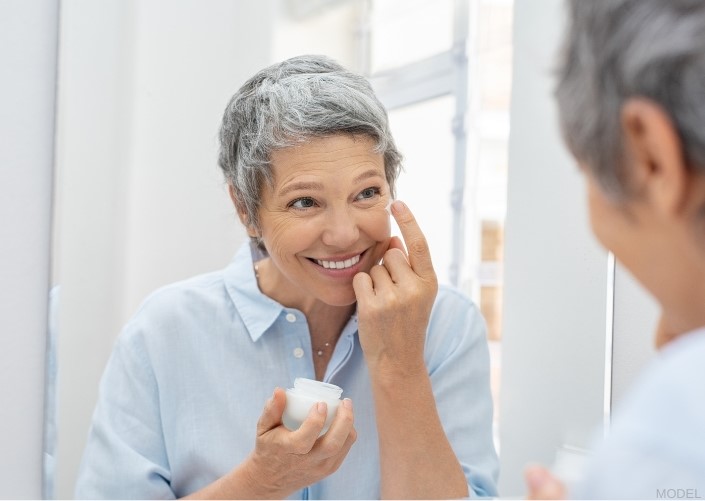 middle aged woman applying facial cream