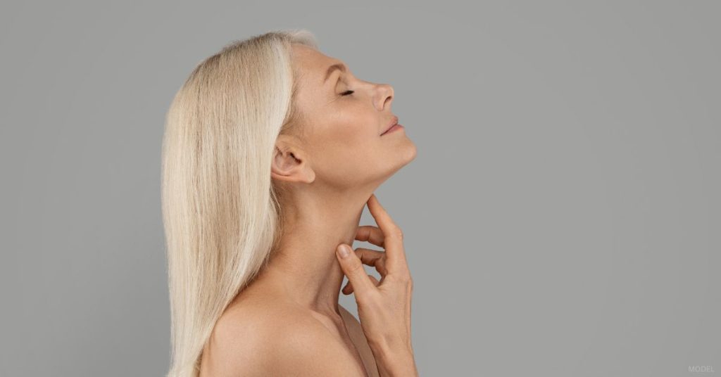A woman with long blonde hair touching their neck. (Model)