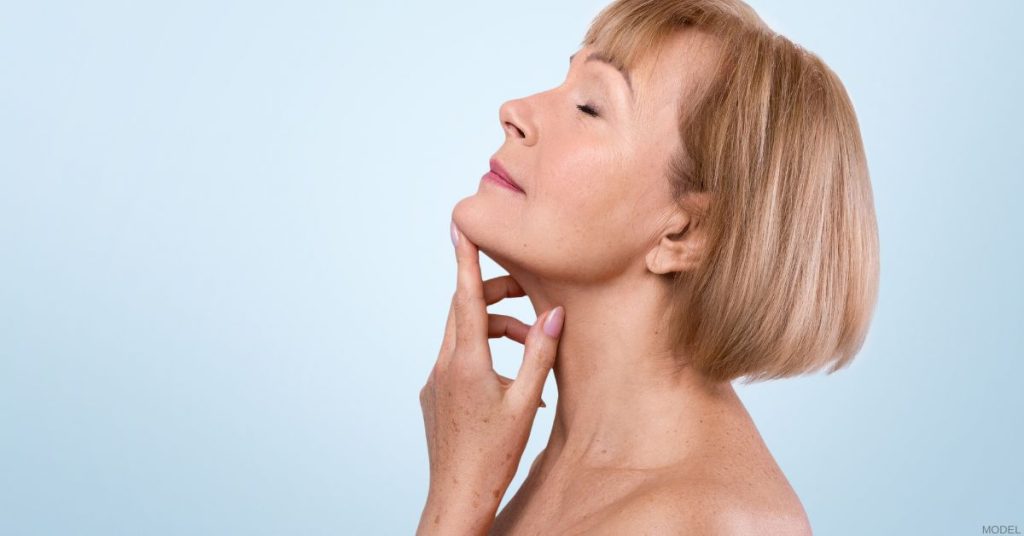 Woman in profile with her head tilted back, touching her chin (model)